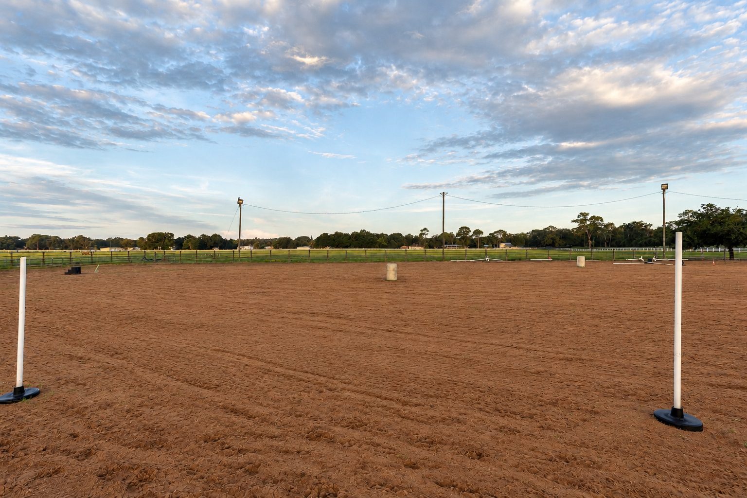 Empty riding arena with pattern poles at Timberlane Stables, at sunset
